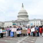 In front of the US Capitol Building, a group of people hold signs