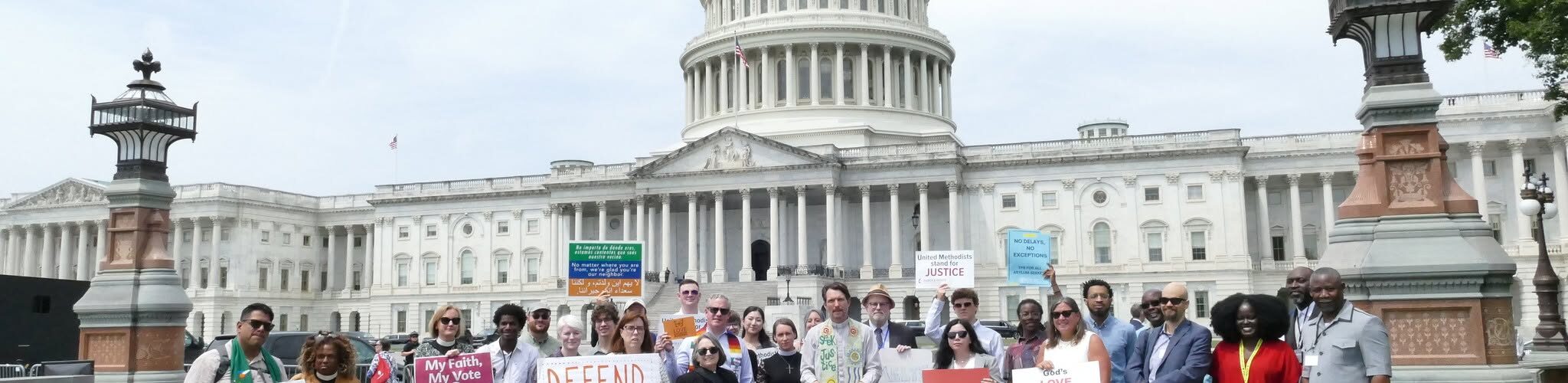 In front of the US Capitol Building, a group of people hold signs