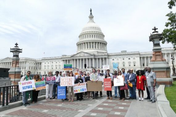 In front of the US Capitol Building, a group of people hold signs