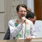 A man with a moustache holding a microphone